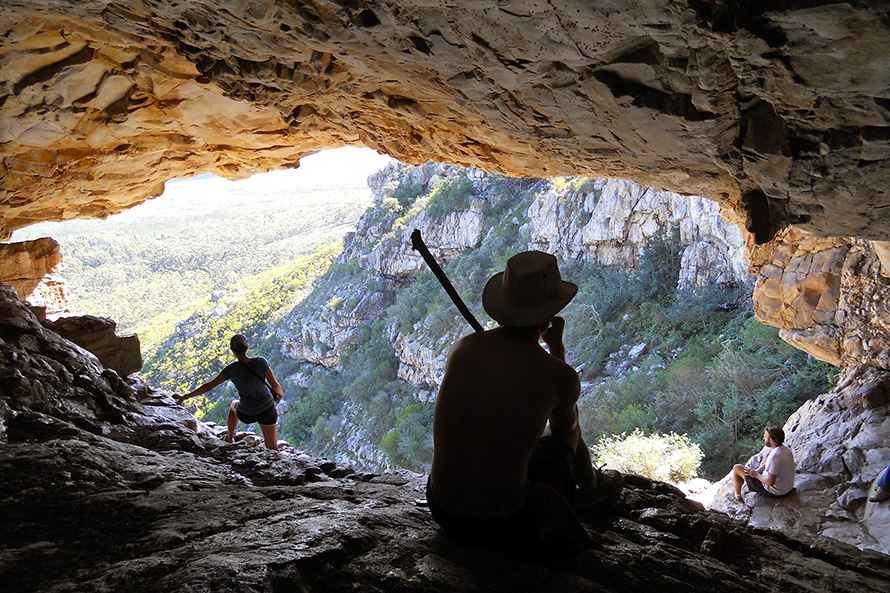 student looks out to the landscape from a natural cave