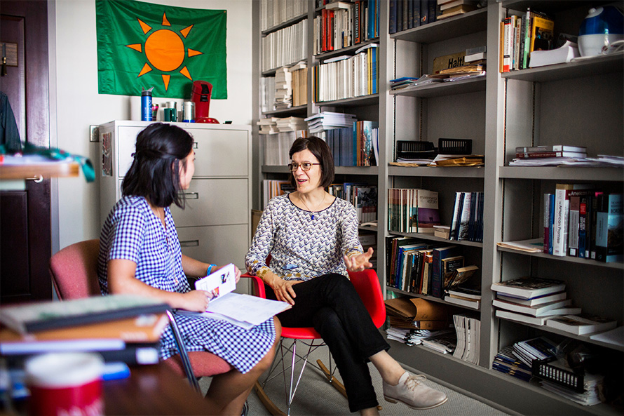 a student and advisor meet in a book-lined office