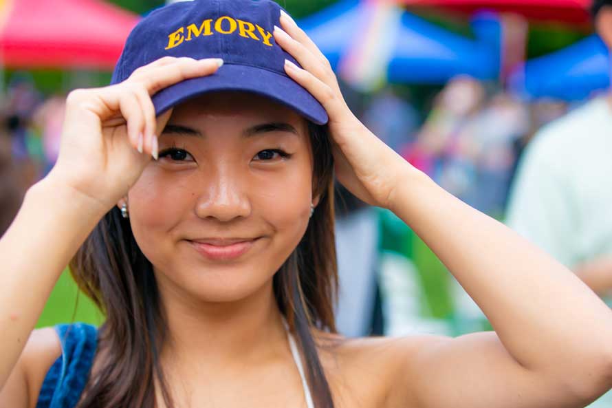 Student posing with Emory hat