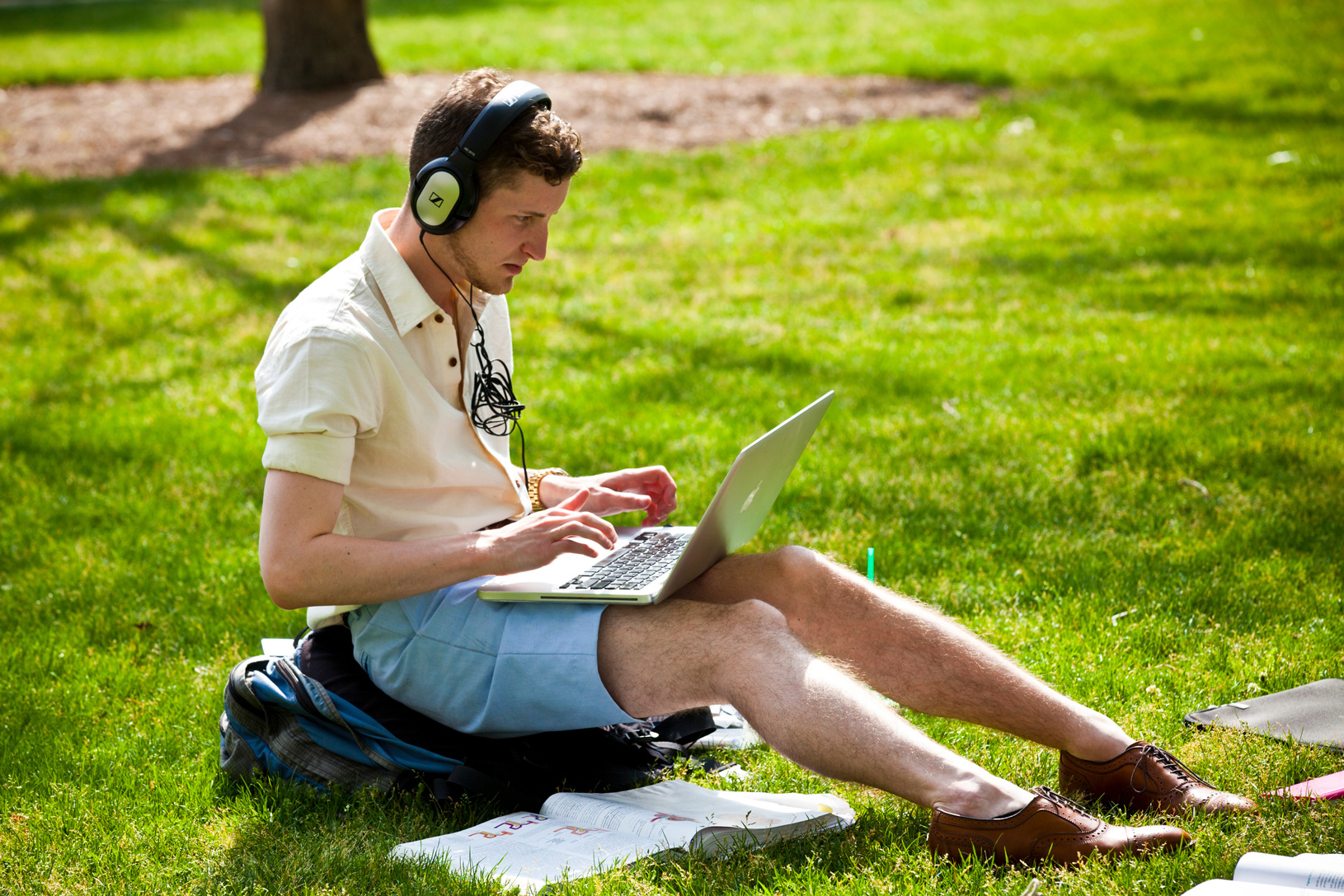 Student with laptop sitting on lawn