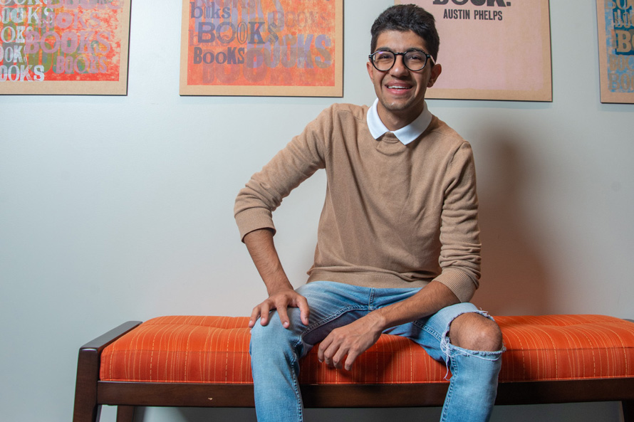 student Shaan Bhasin 25C sits on a bench, smiling